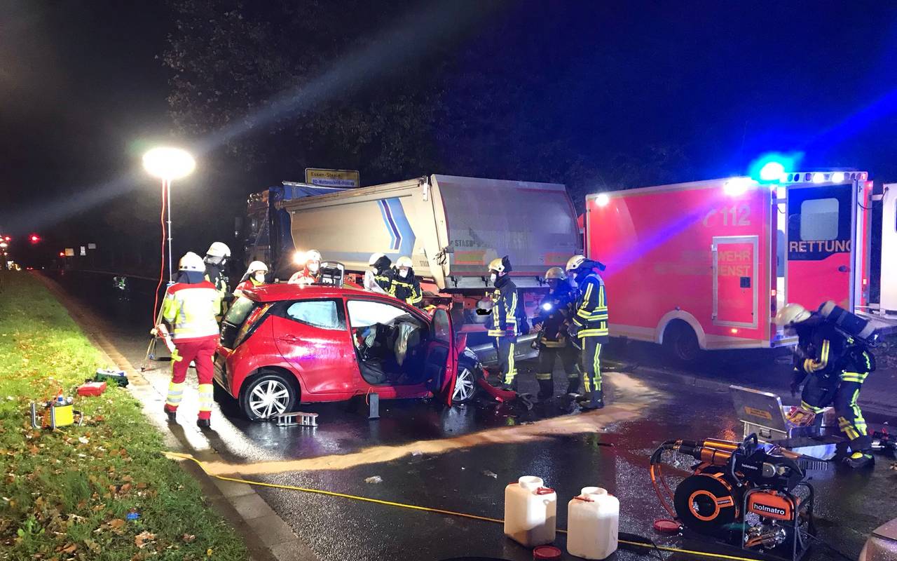 Feuerwehrleute stehen um einen zerbeulten Wagen herum