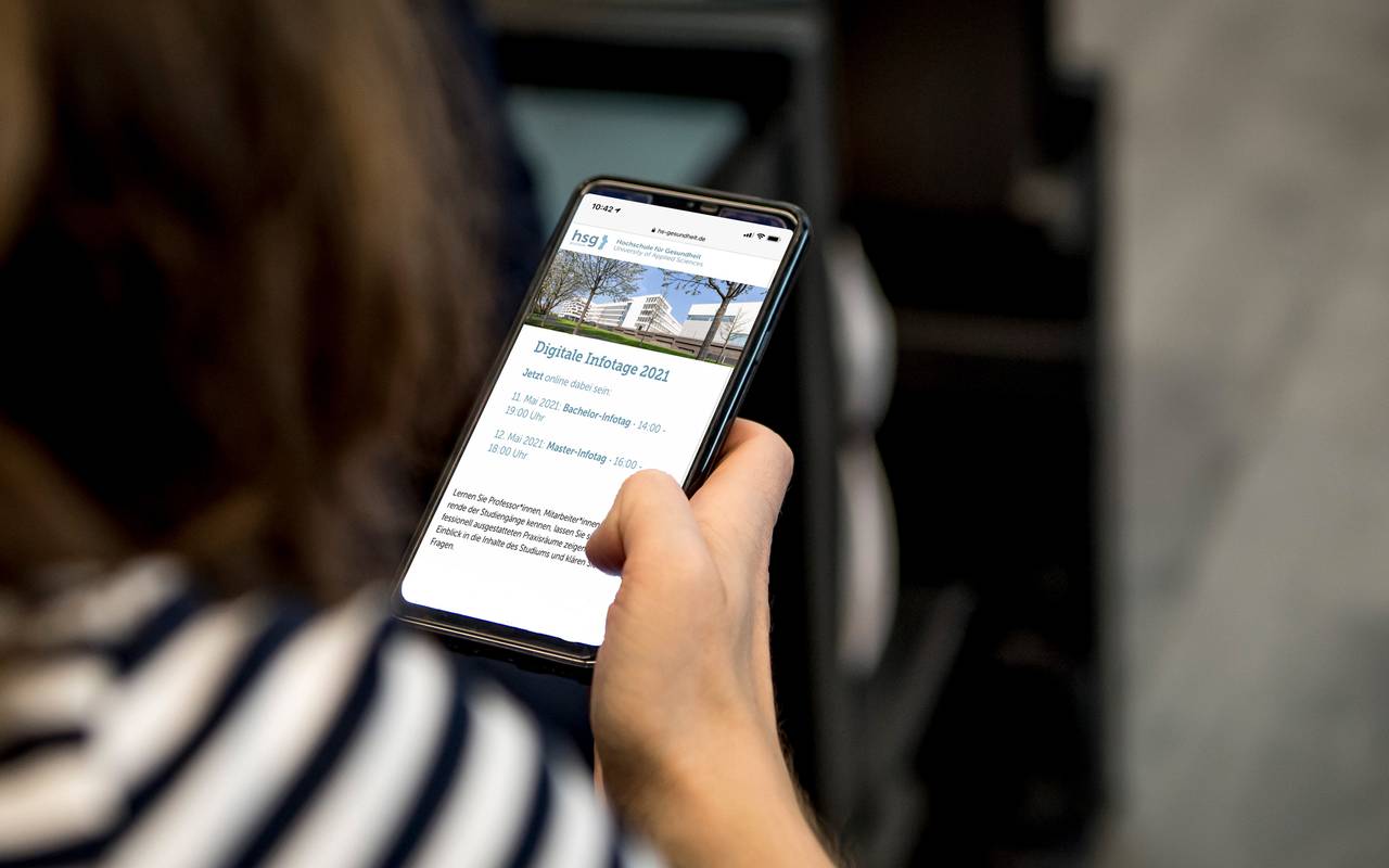 Auf einem Handy wird die Website der Hochschule für Gesundheit angezeigt