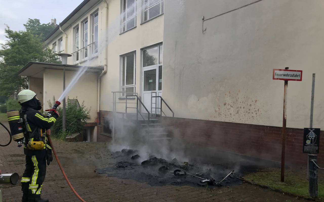 Feuerwehrleute löschen brennende Abfallbehälter