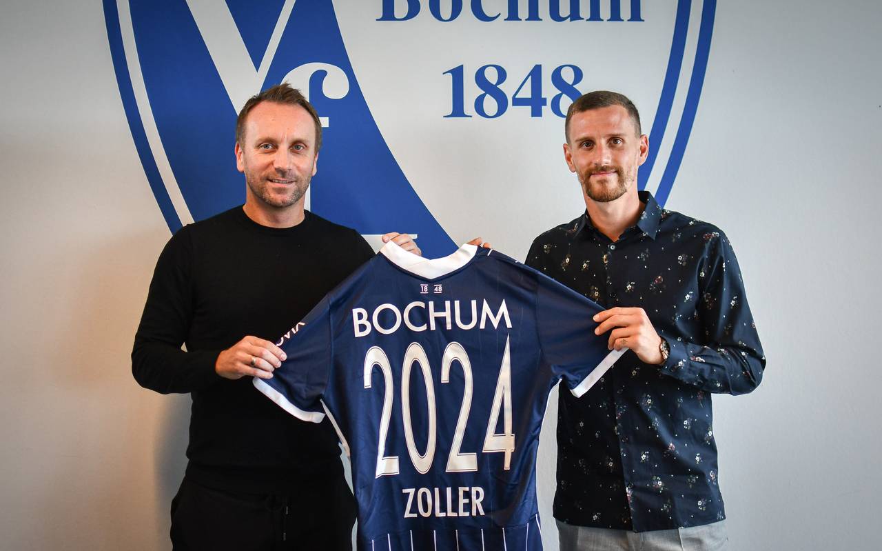 Zwei Männer lächeln in die Kamera und halten ein VfL-Trikot in den Händen.
