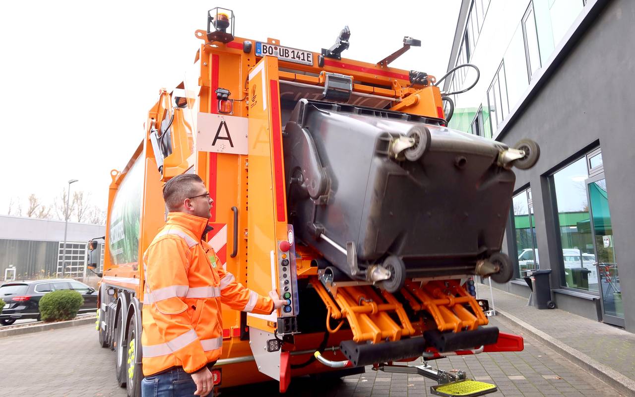 Elektro-Müllwagen kippt Papiertonne