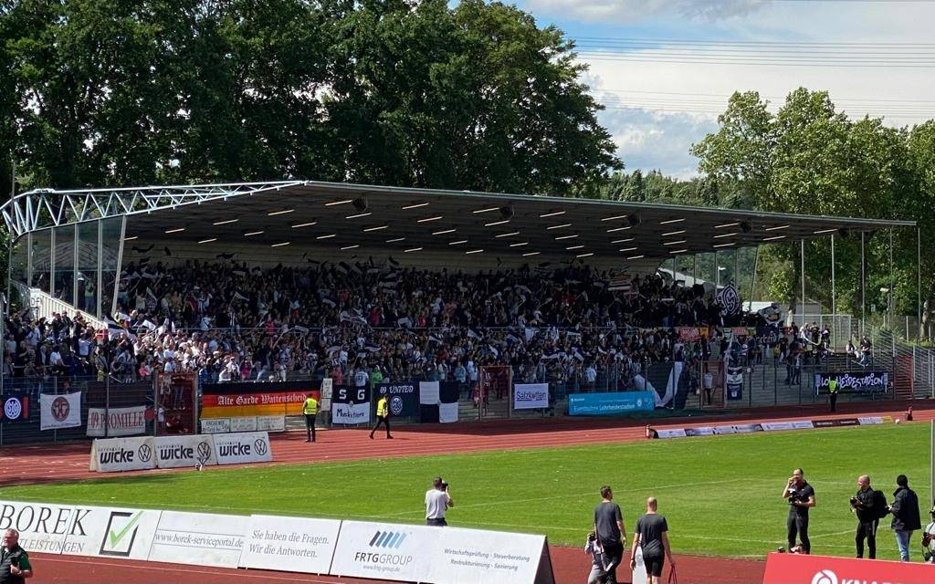Viele Menschen schwenken mit Fahnen auf einer Tribüne
