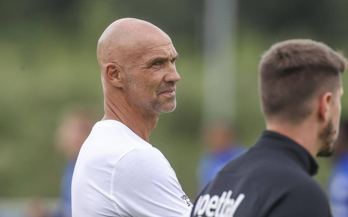Mann in weißem T-Shirt und mit Glatze schaut zur Seite.