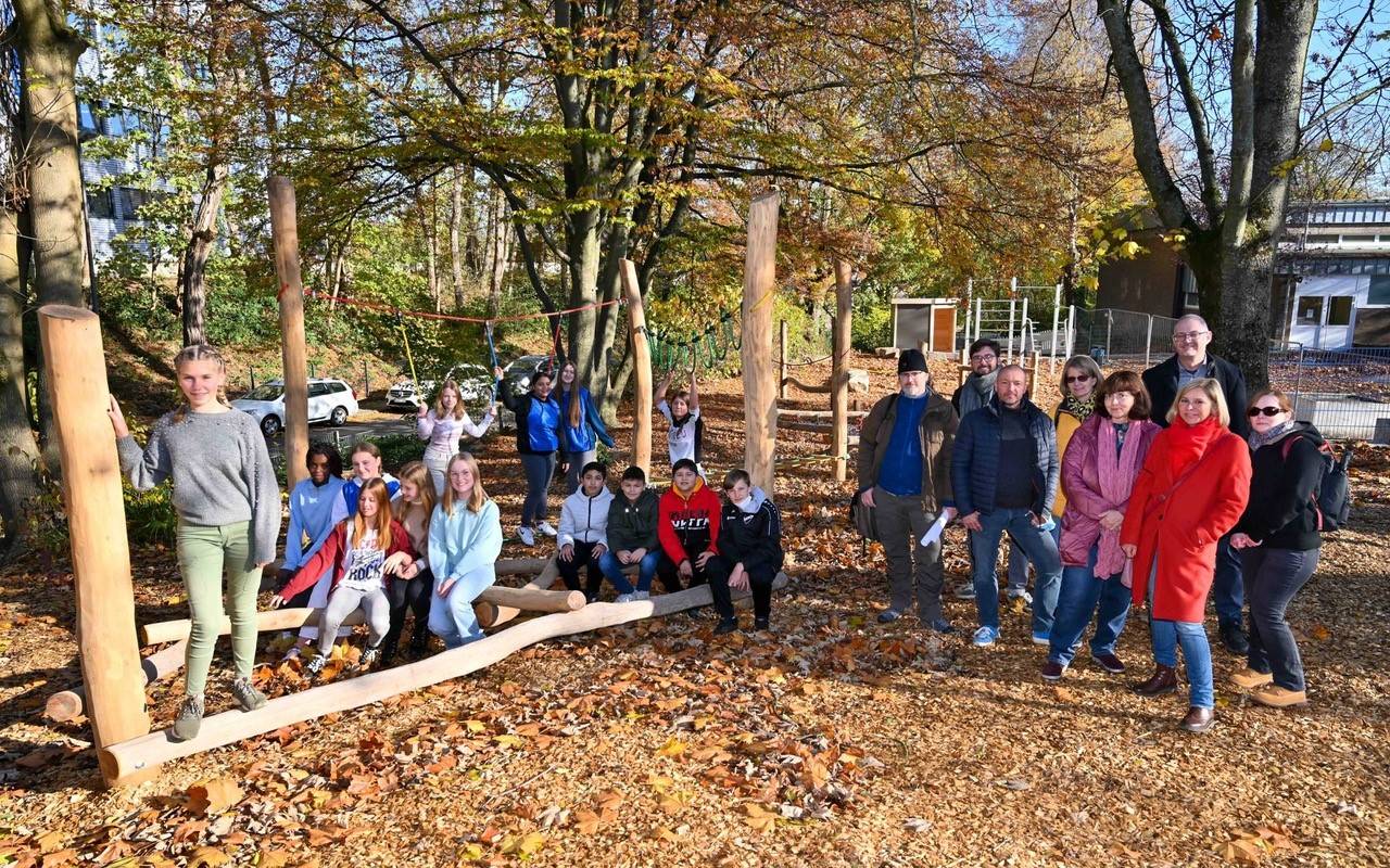 Viele Menschen lächeln auf einem Schulhof in die Kamera.