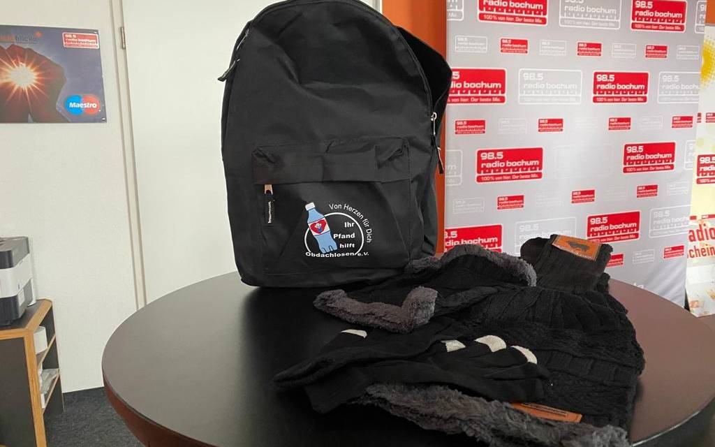 Schwarzer Rucksack, davor liegt schwarze Winterkleidung