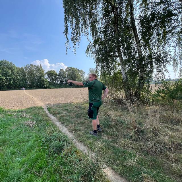 Dort wo eigentlich der Blühstreifen für Wildpflanzen und -tiere blühen sollte, steht Der Wattenscheider Landwirt Patrick Appelbaum und ärgert sic über Trampelpfade durch Fuß- und Spaziergänger:innen.