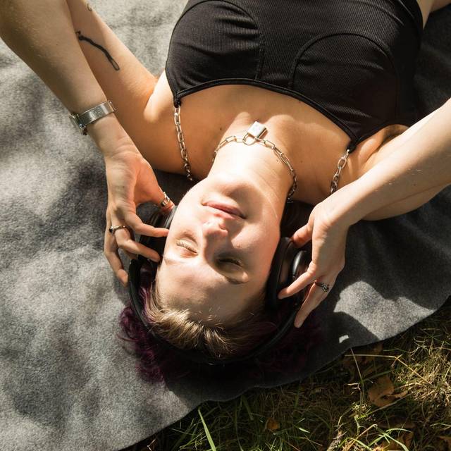 Eine diverse Person mit Kopfhörern im Park