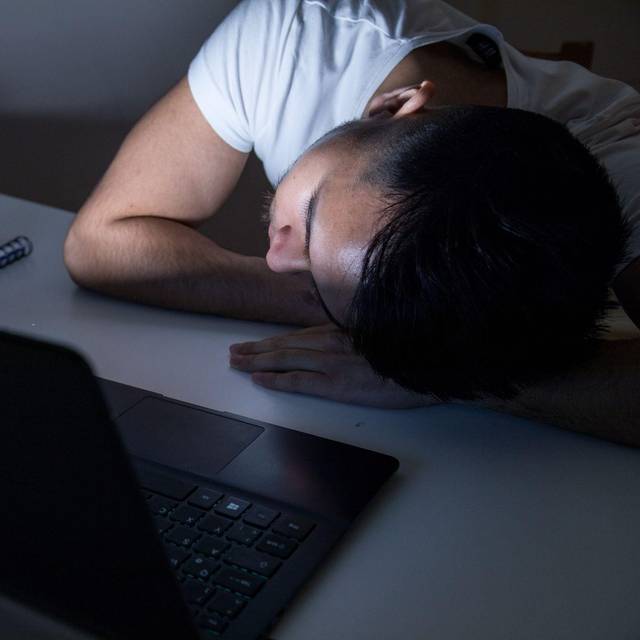 Mann legt erschöpft seinen Kopf auf den Tisch