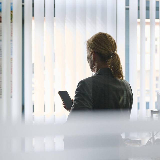 Frau steht im Büro und telefoniert mit einem Headset