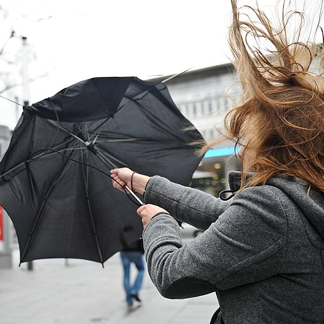 Eine Frau kämpft mit ihrem Regenschirm in der Essener Innenstadt gegen die Windböen eines Sturms.