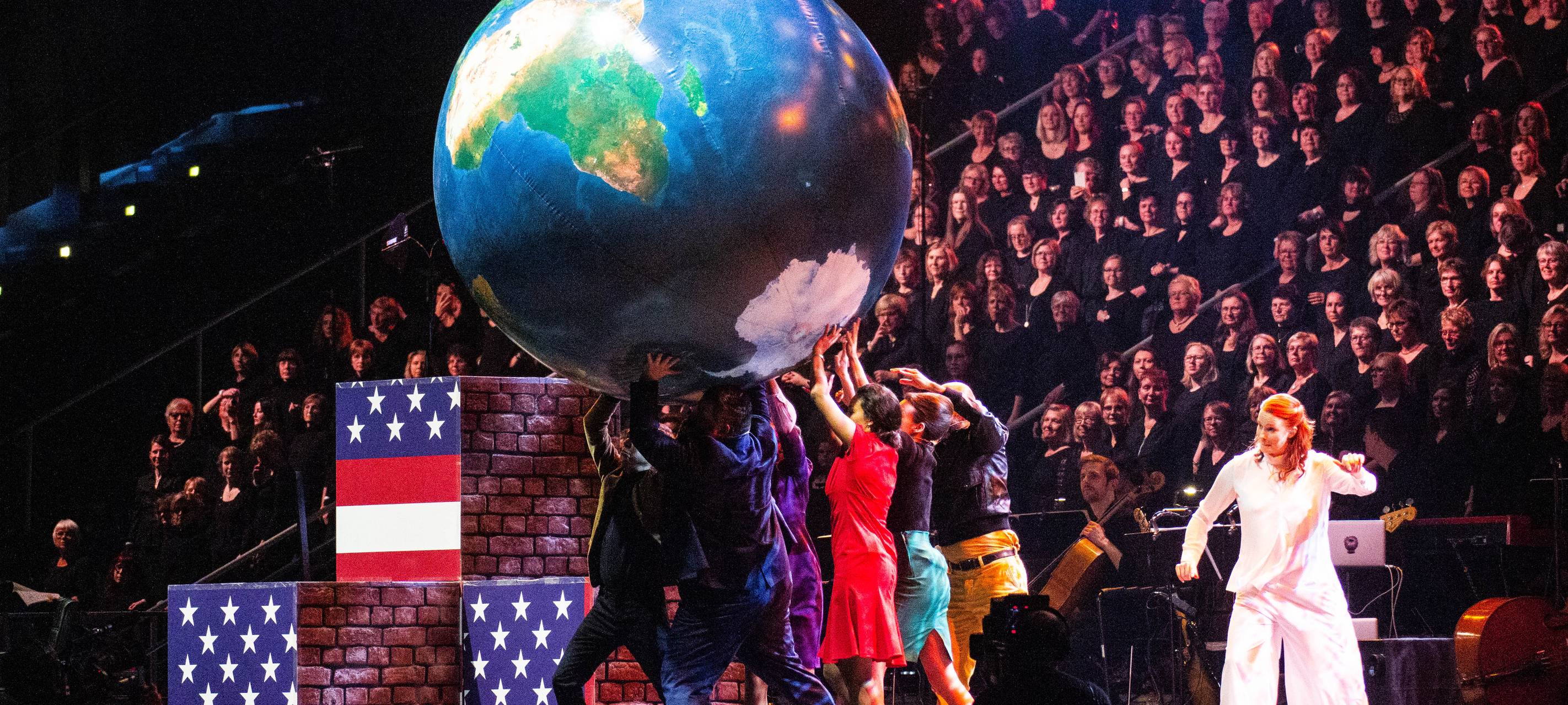 Schauspieler auf der Bühne; großer Chor im Hintergrund