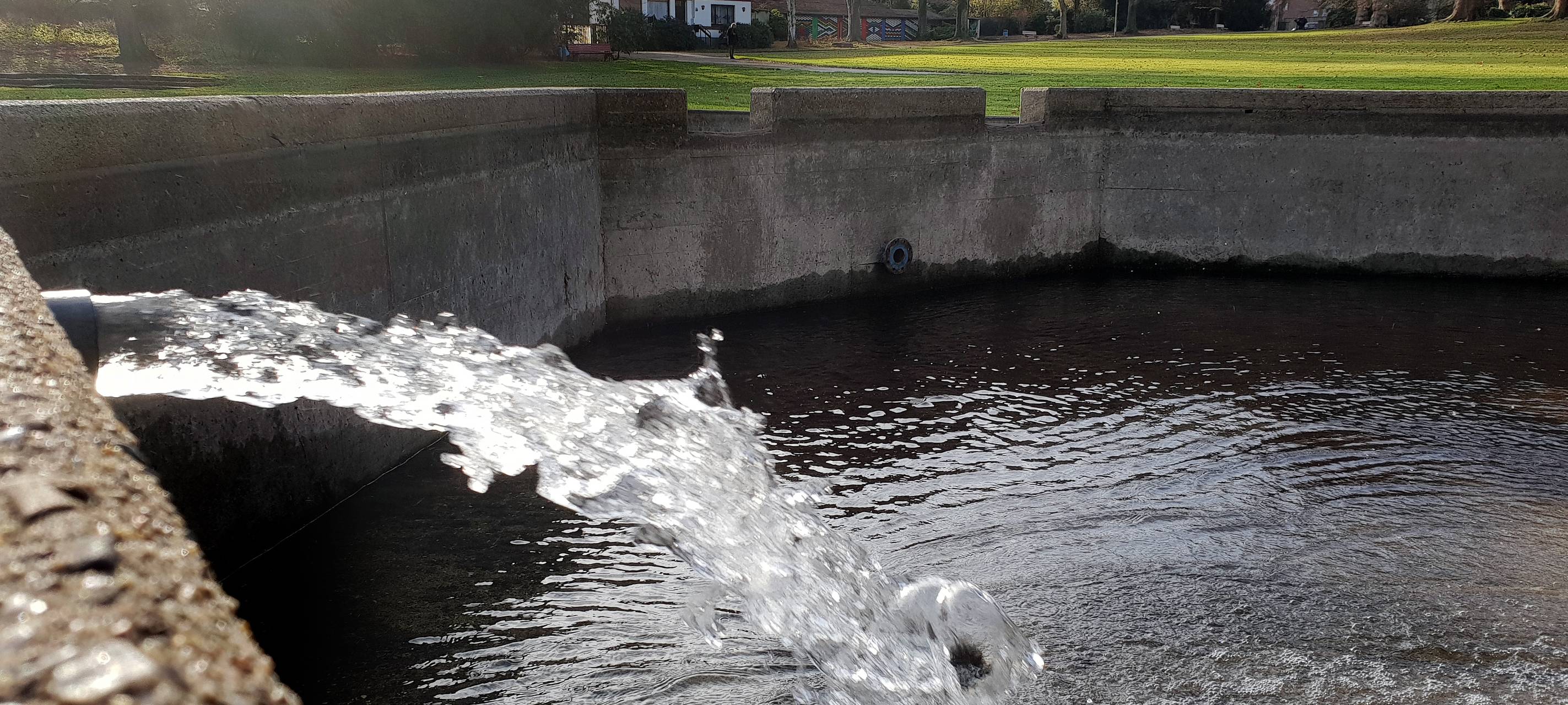 Wasser fließt aus einem Trichter in einen Brunnen