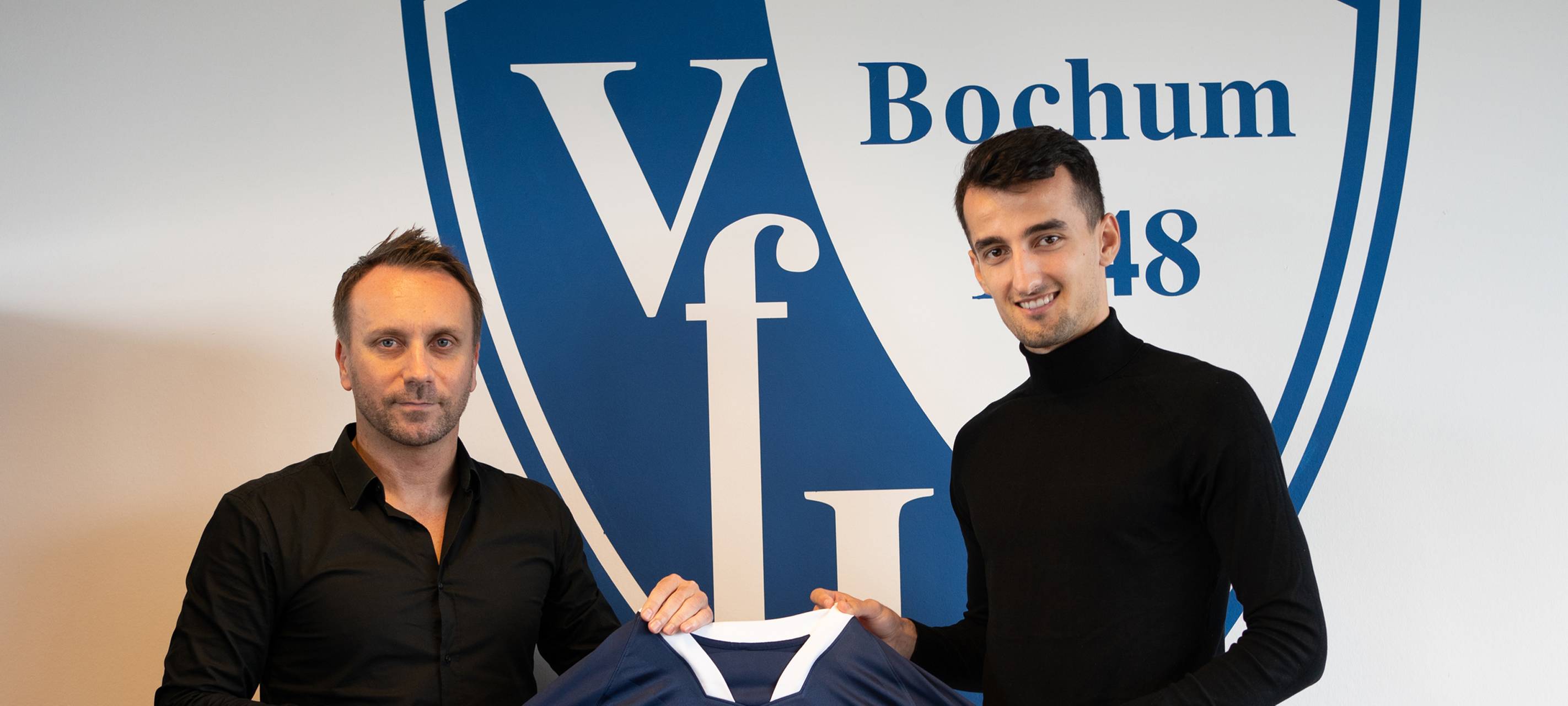 Zwei Männer lächeln und halten ein VfL Trikot in die Kamera