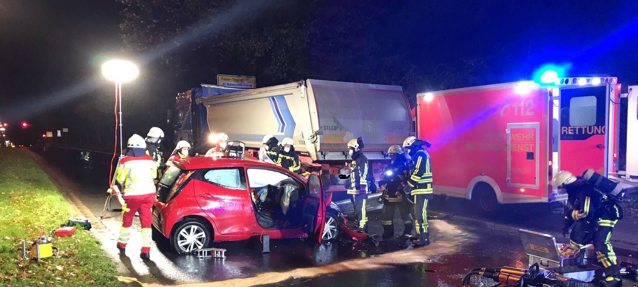 Feuerwehrleute stehen um einen zerbeulten Wagen herum