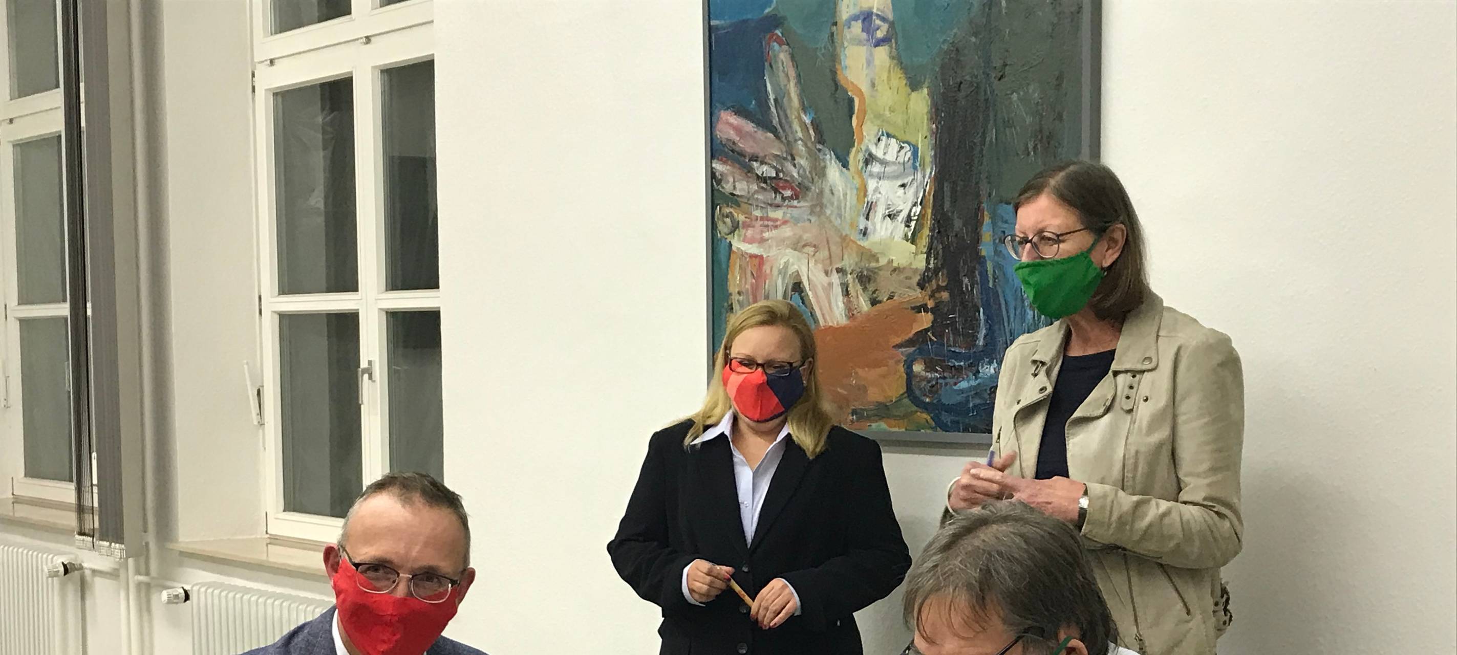 Vier Menschen sind mit Mundschutz über einen Vertrag gebeugt.