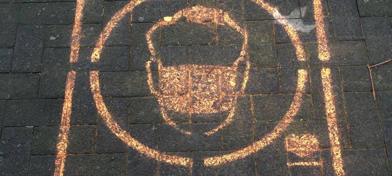 Ein Graffiti auf dem Pflaster der Fußgängerzone weist auf die Maskenpflicht hin.