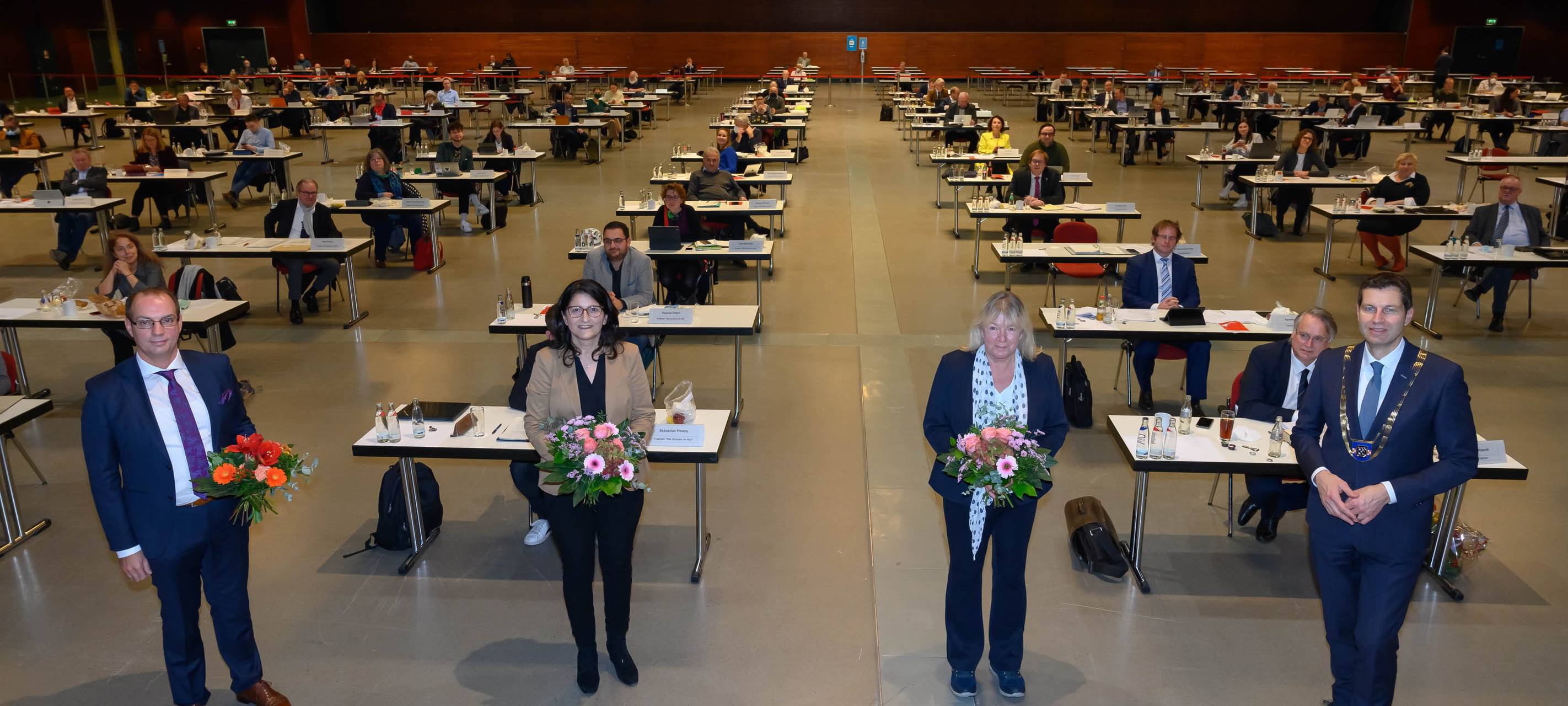 Oberbürgermeister Eiskirch und die 3 neuen ehrenamtlichen Stellvertreter Dewender, Demir und Schäfer stehen mit Blumensträußen in der Hand  im Ruhrcongress.