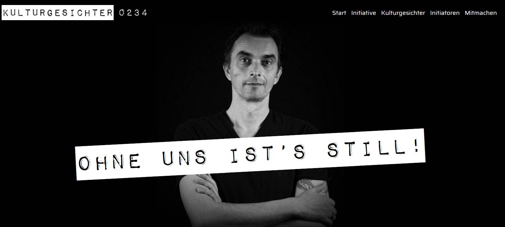 Ein Künstler steht vor schwarzem Hintergrund. Darüber der Slogan Ohne uns ists still.