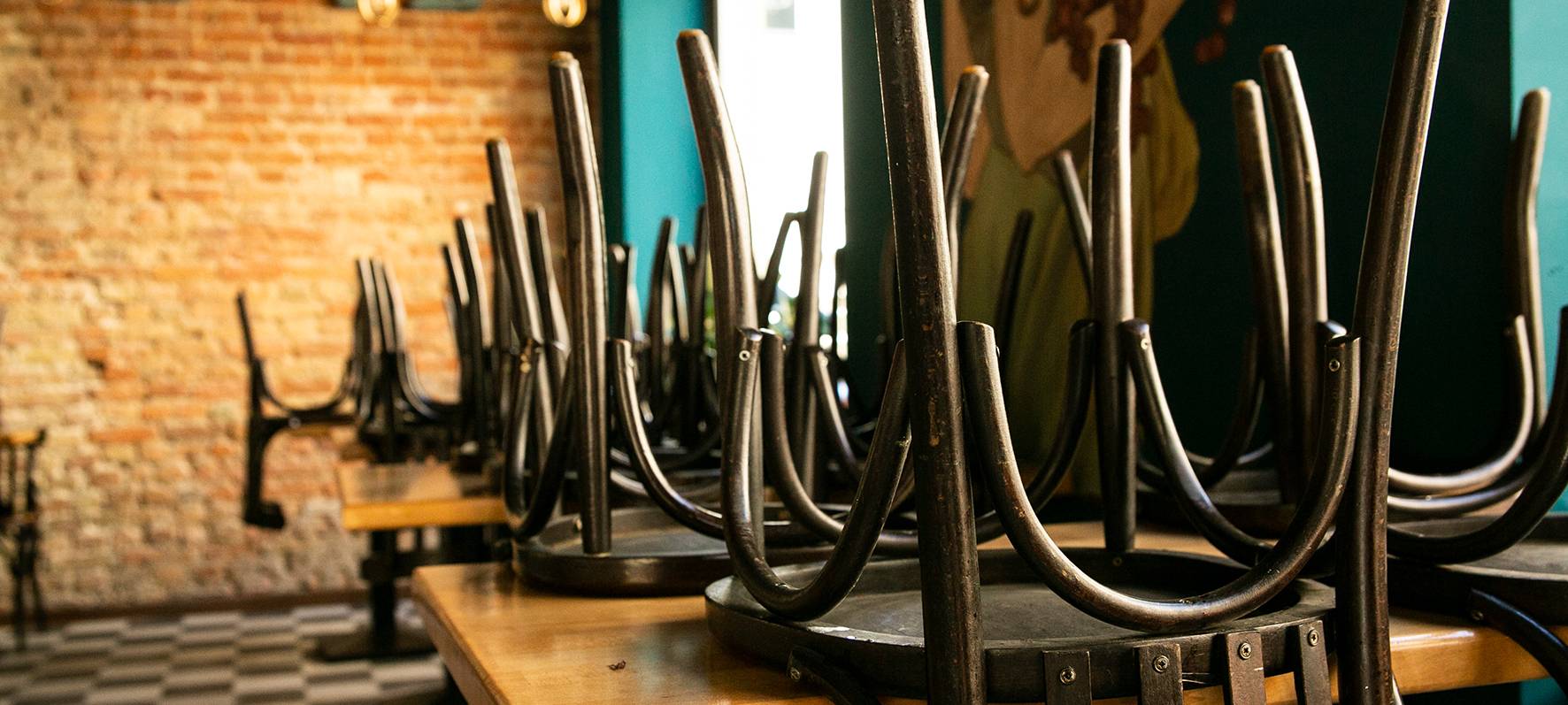 In einer Gaststätte sind leere Stühle umgedreht auf Tische gestapelt.