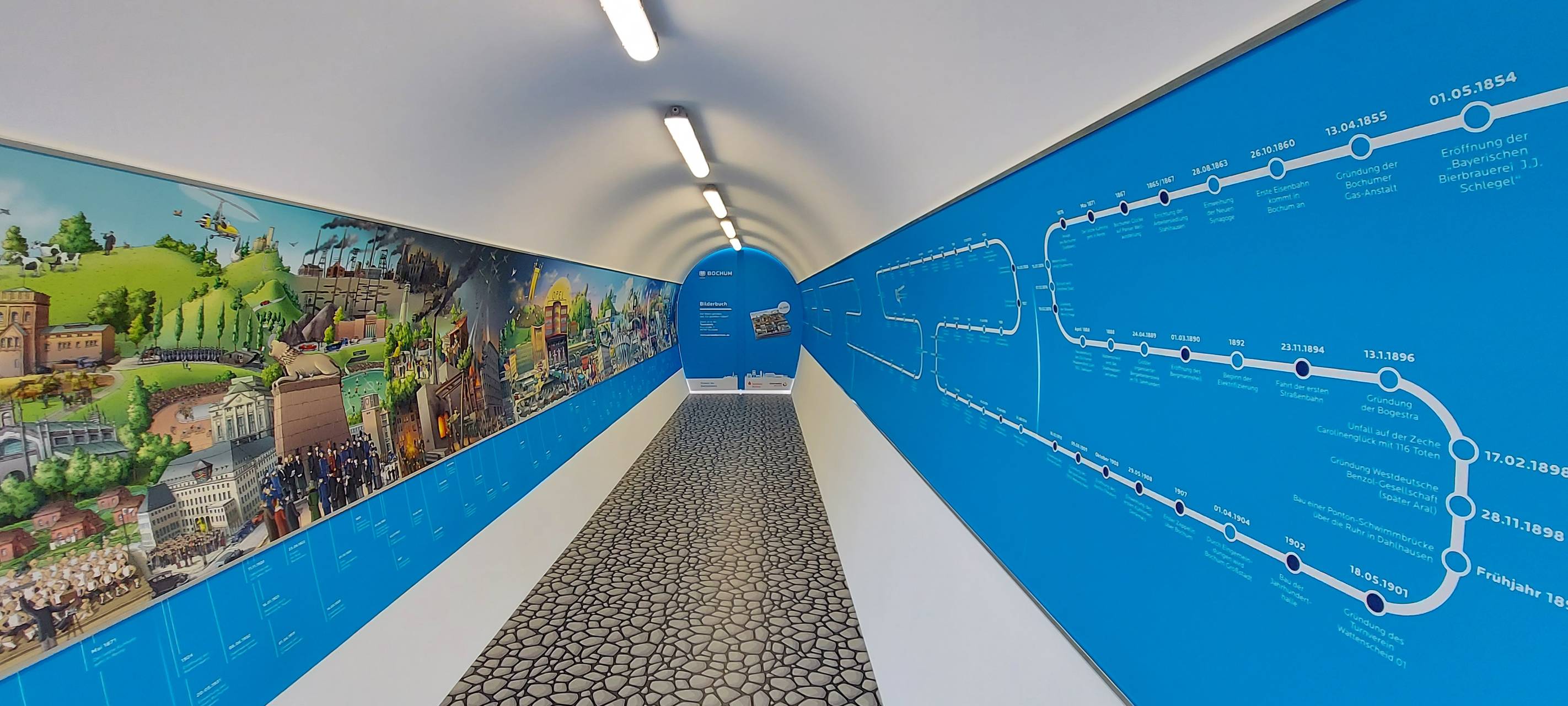 Langer Tunnel mit einem Wimmelbild auf der linken Seite.