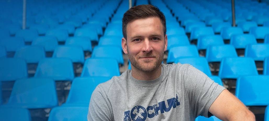 Michael Esser sitzt auf einer Bank und lächelt in die Kamera