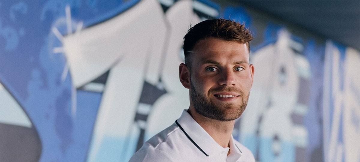 Junger Mann lächelt in die Kamera.