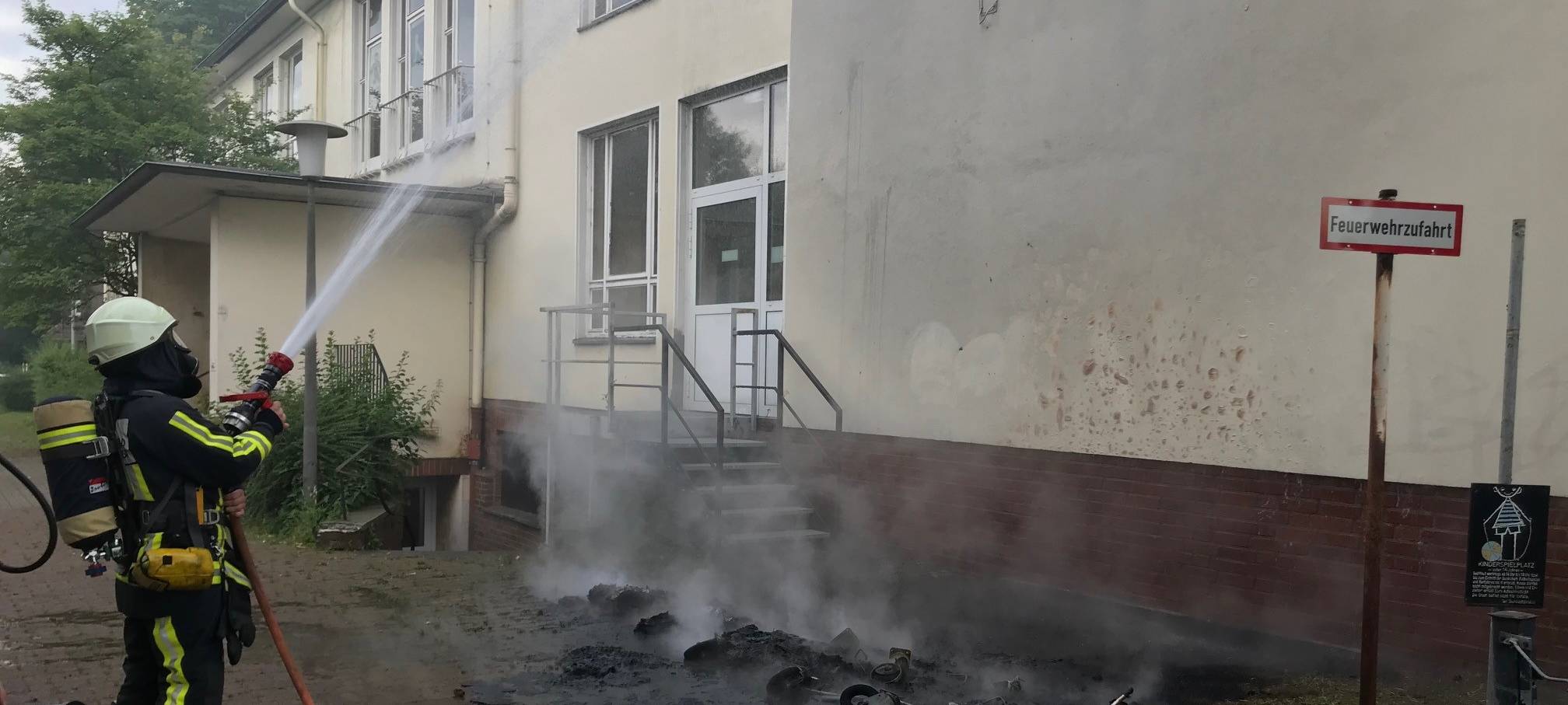 Feuerwehrleute löschen brennende Abfallbehälter