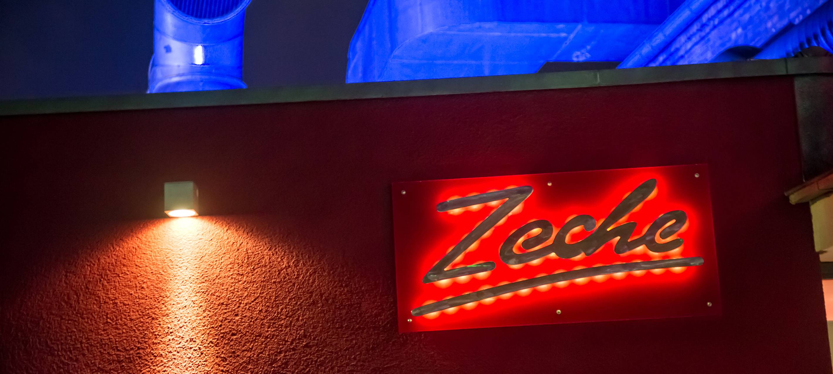Das Logo "Zeche" leuchtet rot im Dunkeln