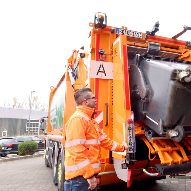 Elektro-Müllwagen kippt Papiertonne