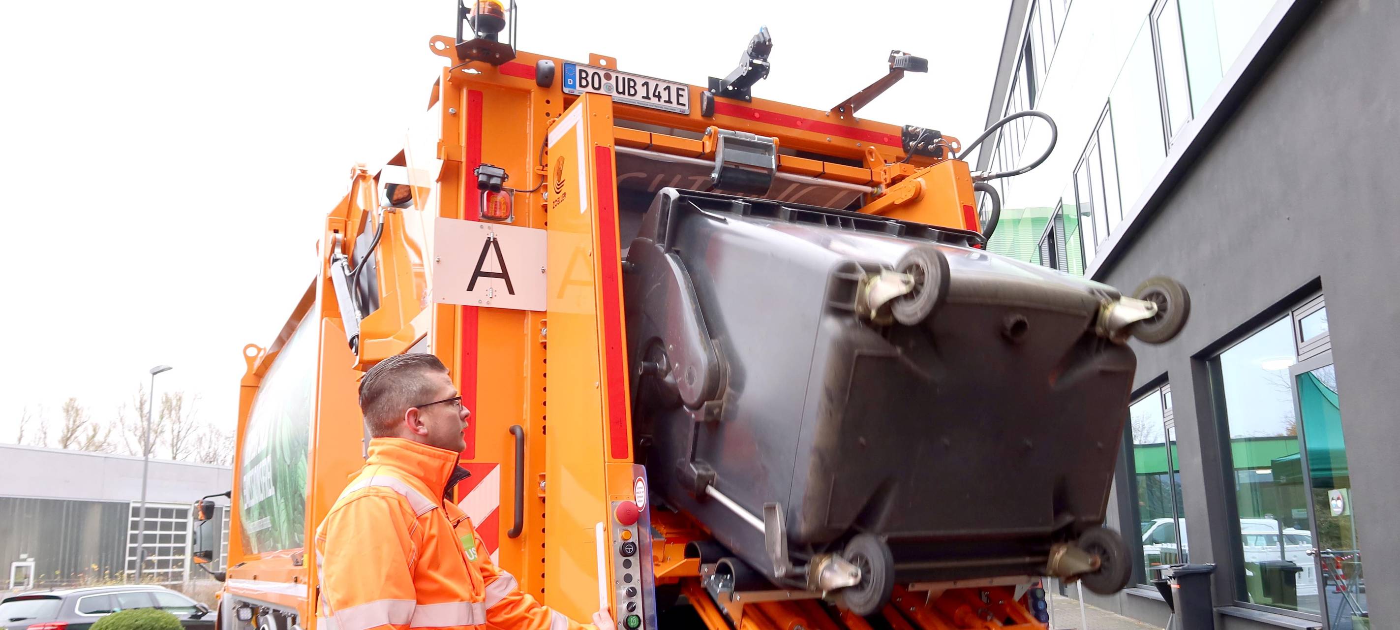 Elektro-Müllwagen kippt Papiertonne