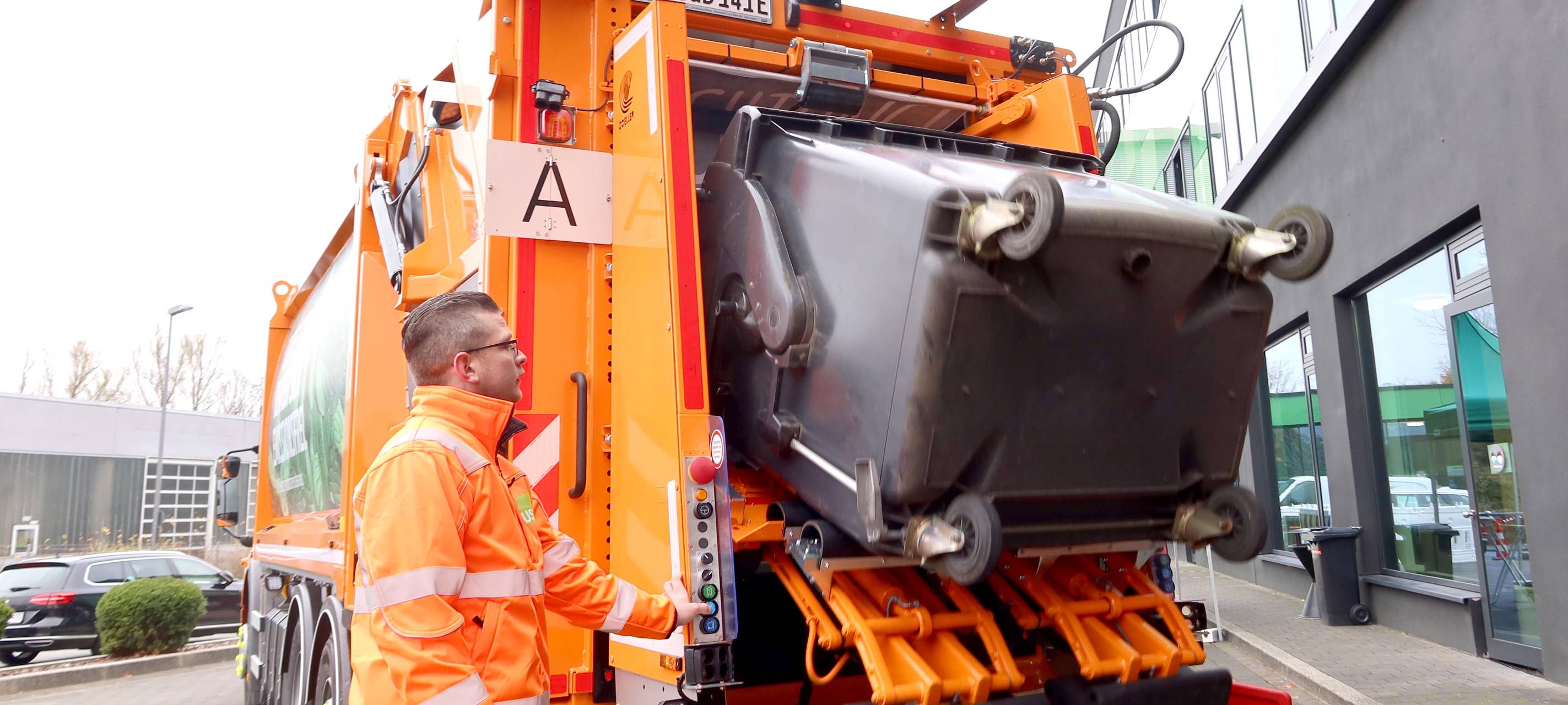 Elektro-Müllwagen kippt Papiertonne