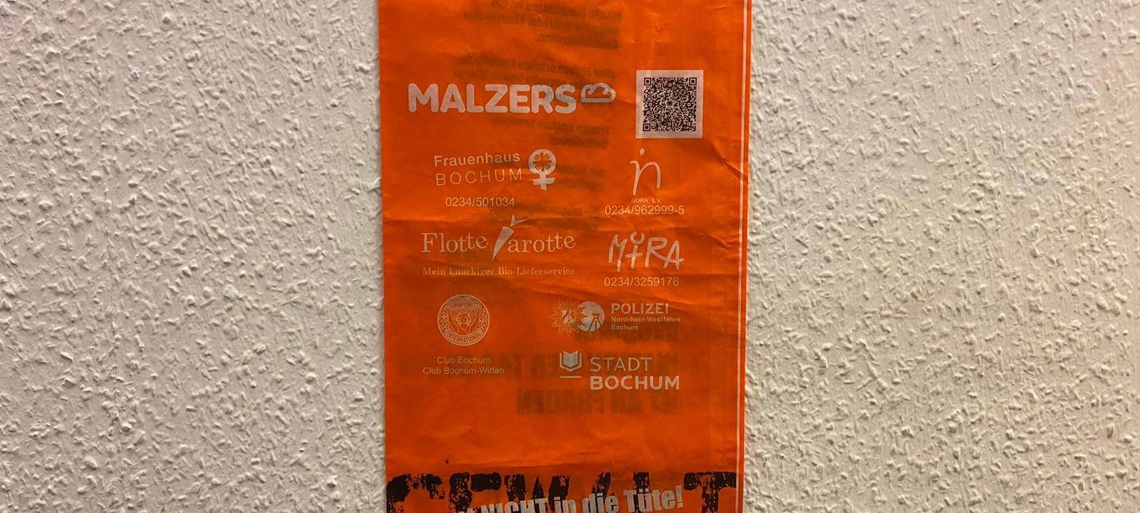Orangene Brötchentüte mit der Aufschrift "Gewalt kommt nicht in die Tüte.