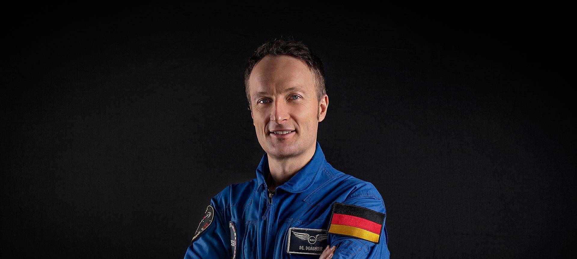 Mann in blauem Anzug lächelt in die Kamera.