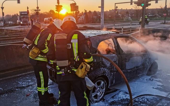 Feuerwehrmänner sprühen Schaum über ein Auto