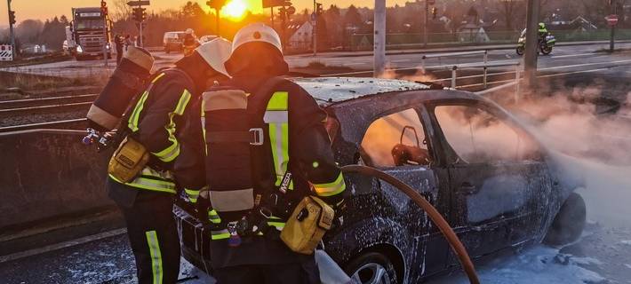 Feuerwehrmänner sprühen Schaum über ein Auto