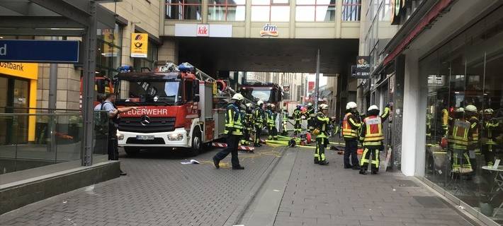 Viele Feuerwehrleute stehen an einem Feuerwehrauto in der Innenstadt.