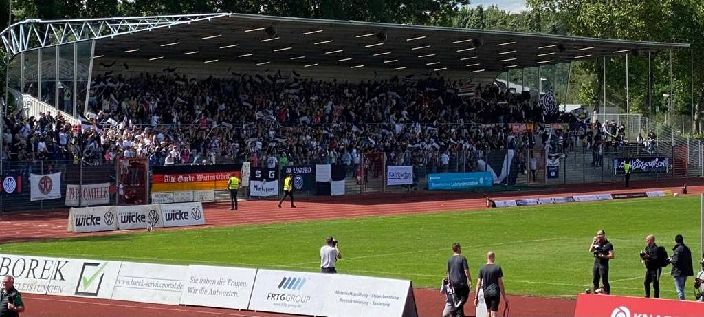 Viele Menschen schwenken mit Fahnen auf einer Tribüne