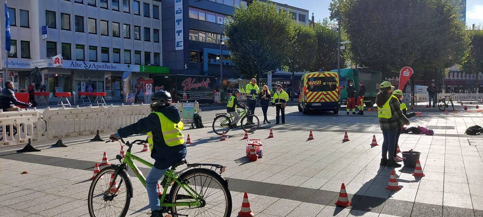 Kind mit gelber Warnweste sitzt auf einem Fahrrad