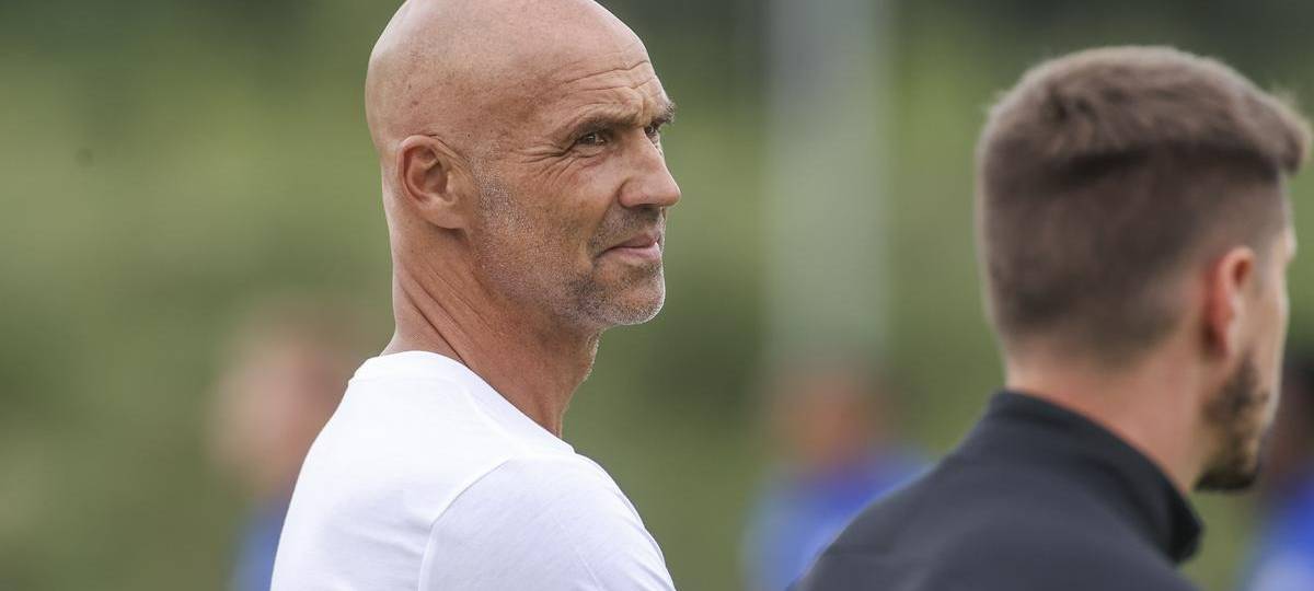 Mann in weißem T-Shirt und mit Glatze schaut zur Seite.