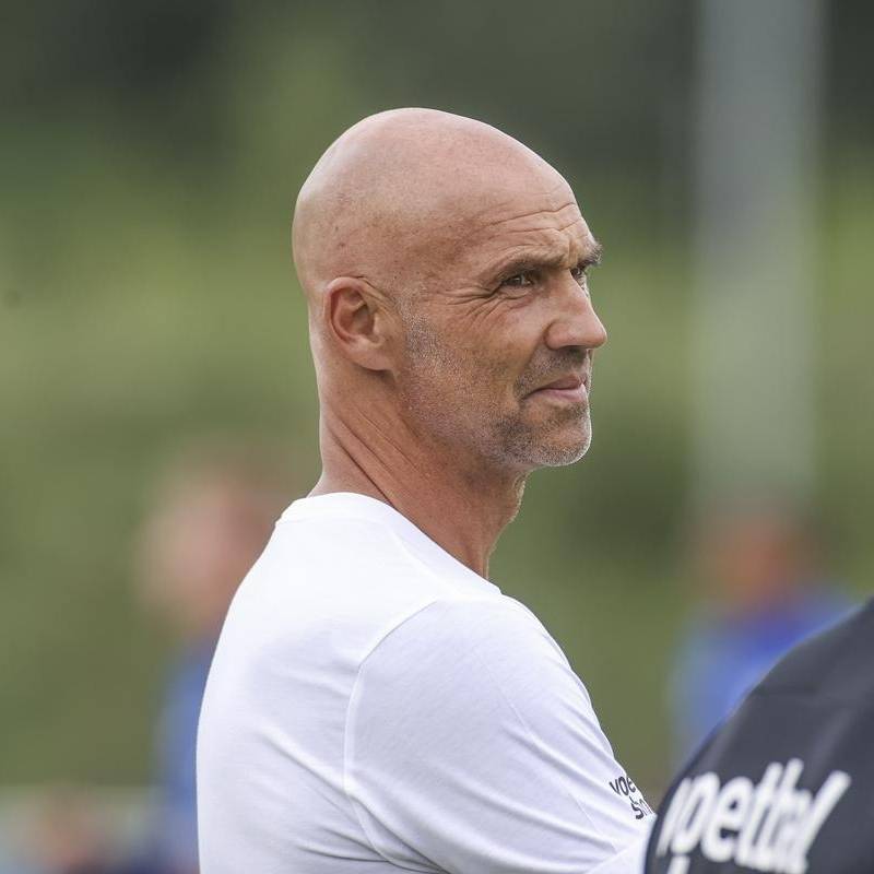 Mann in weißem T-Shirt und mit Glatze schaut zur Seite.