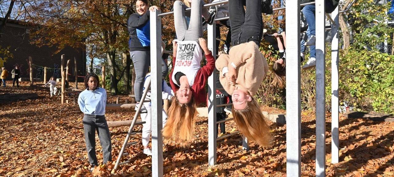 Kinder hängen Kopfüber am Klettergerüst.