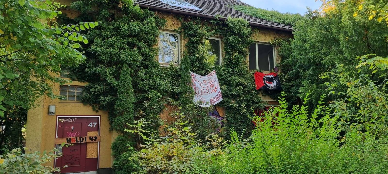 Haus aus dessen Fenstern Plakate hängen
