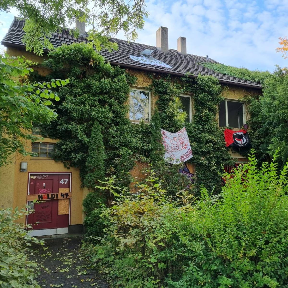 Haus aus dessen Fenstern Plakate hängen