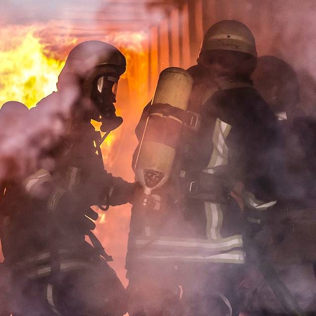 Feuerwehrleute im Einsatz vor einem großen Feuer in einem Keller.