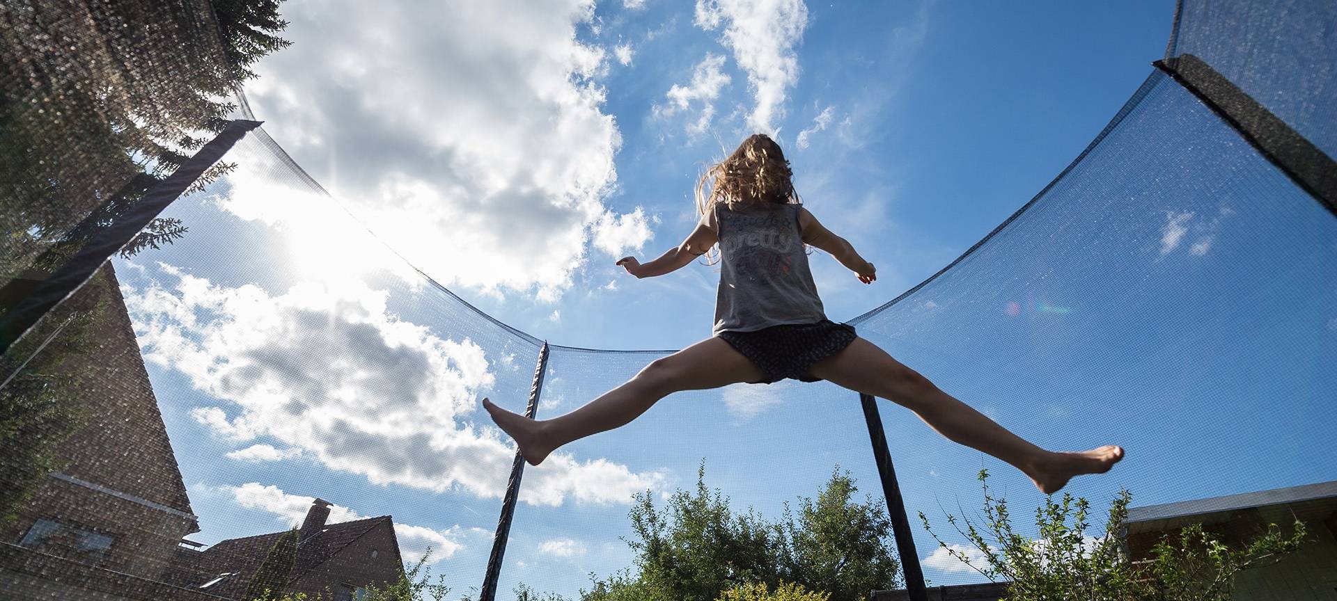 Ein Mädchen springt in einem Garten auf einem Trampolin