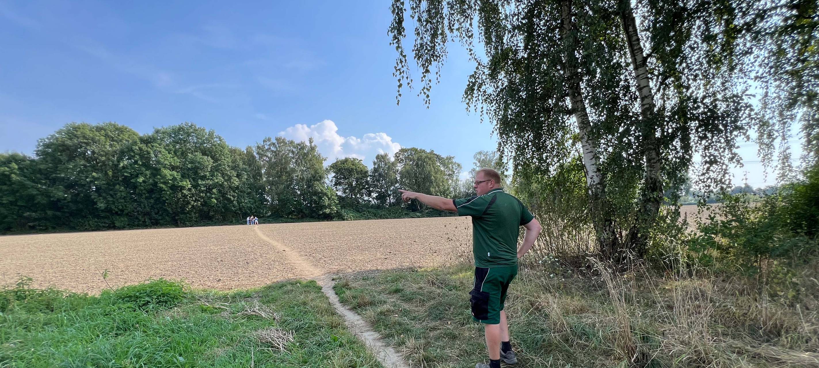 Dort wo eigentlich der Blühstreifen für Wildpflanzen und -tiere blühen sollte, steht Der Wattenscheider Landwirt Patrick Appelbaum und ärgert sic über Trampelpfade durch Fuß- und Spaziergänger:innen.