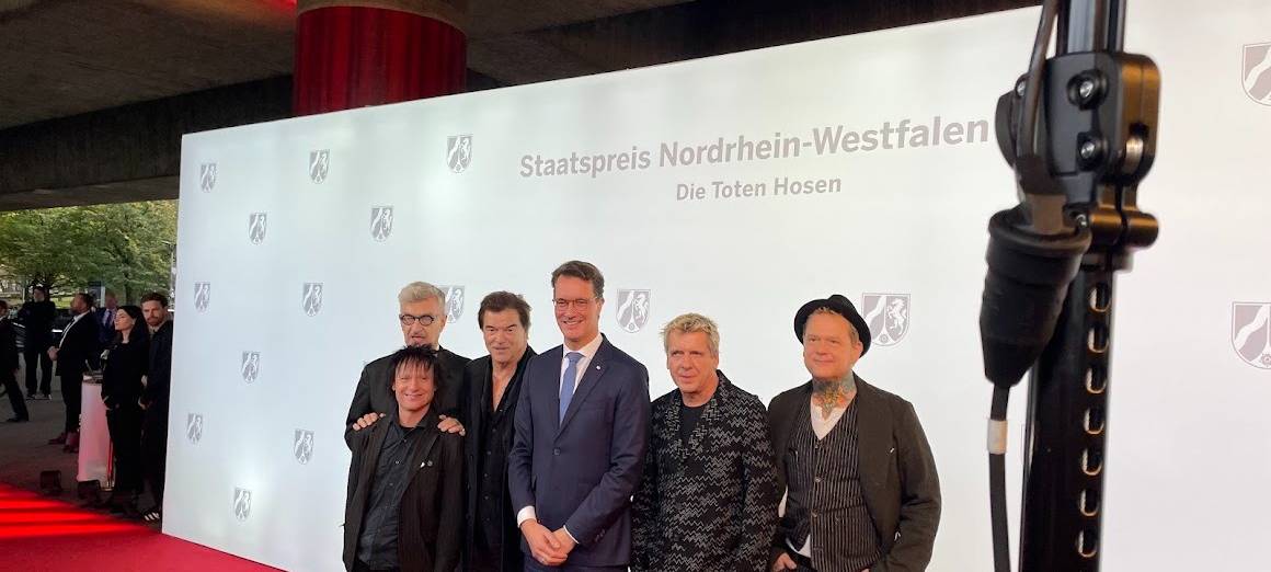 Die Toten Hosen und NRW-Ministerpräsident Hendrik Wüst auf dem rote Teppich. Die Toten Hosen bekommen den NRW-Staatspreis für  ihr kulturelles Lebenswerk und für ihre sozialen Einsatz.