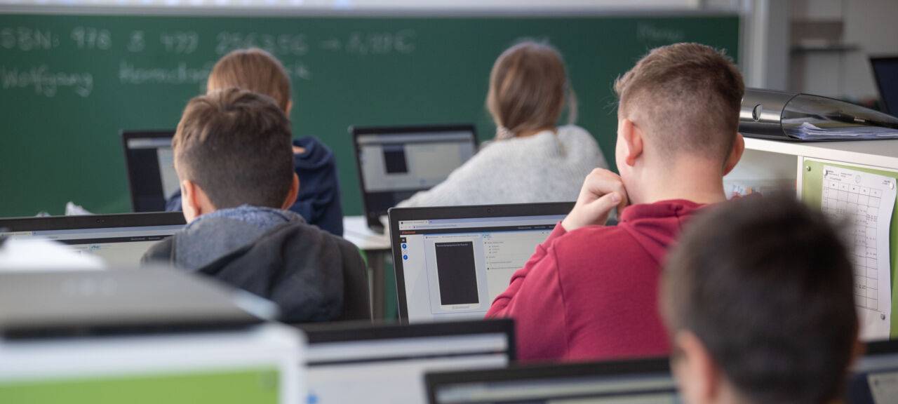 Beschreibung  Schülerinnen und Schüler nehmen im Klassenzimmer einer 9. Klasse der Gemeinschaftsschule Leutenbach am Geografieunterricht mit Hilfe von Laptops und Tablets teil.