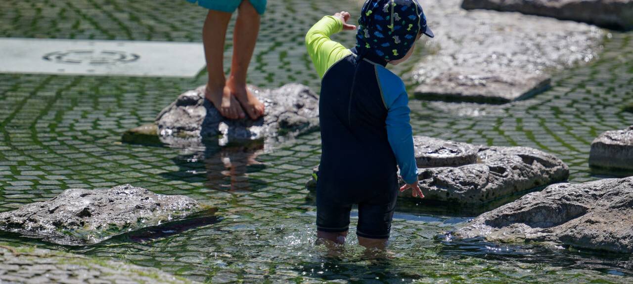 Kinder kühlen sich in einem Brunnen nahe des Rheins ab.