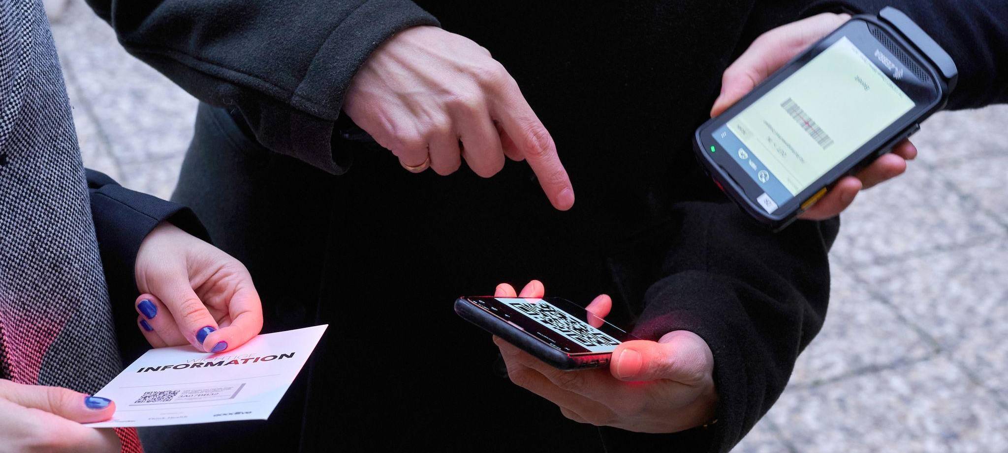 Ein Mann zeigt auf einen QR-Code den eine Frau Scannt